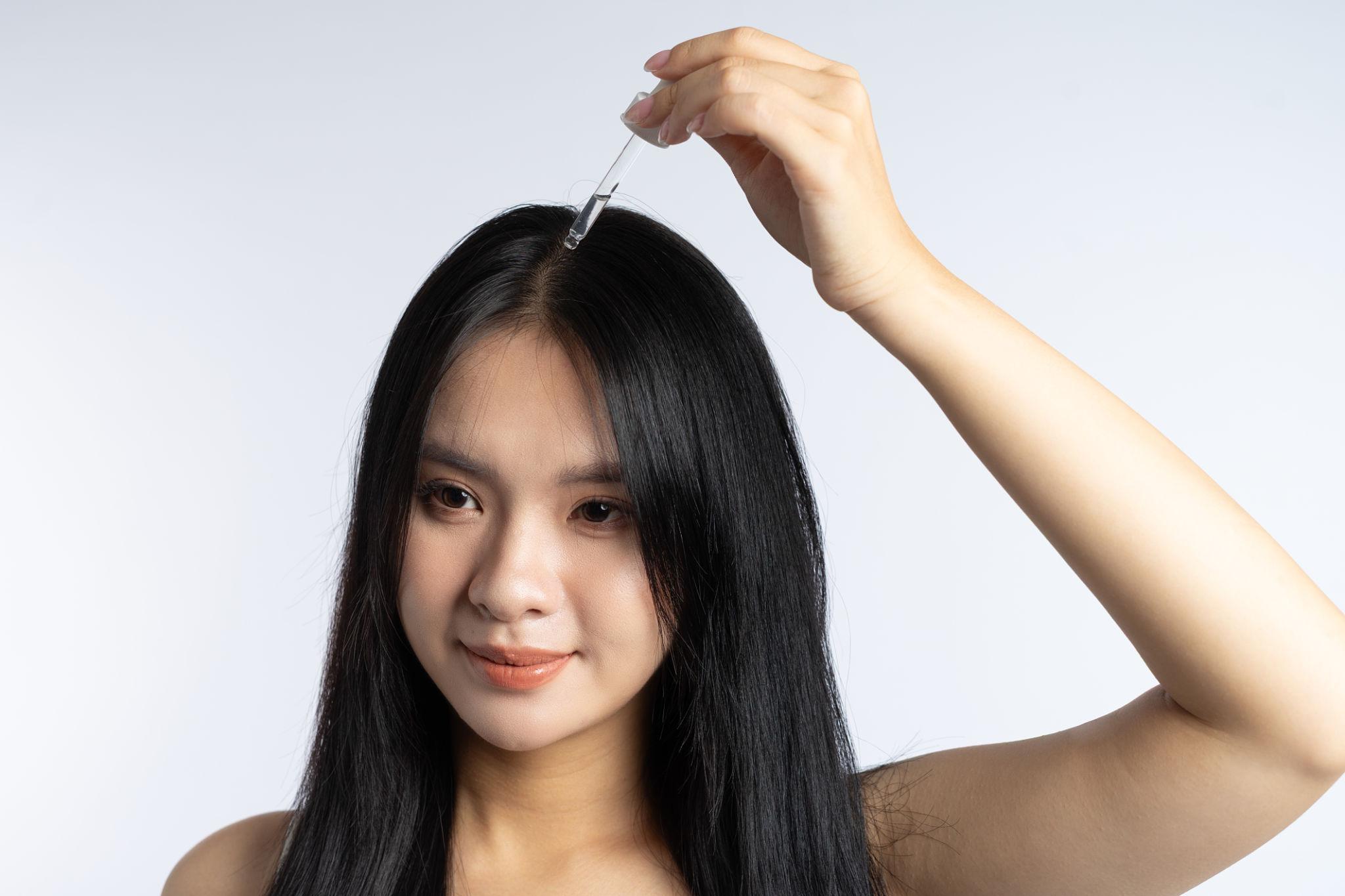 Woman applying hair serum for smooth and frizz free hair